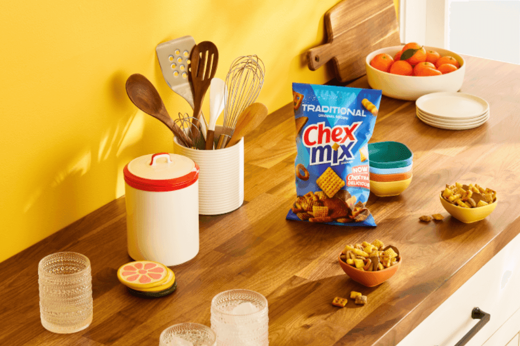 A bag of Chex Mix Traditional Snack Mix on a kitchen countertop with two small ramekins filled with the snack mix